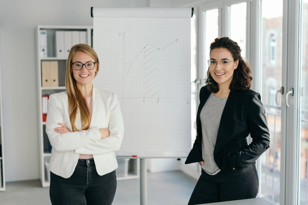 zwei Frauen stehen lächelnd im Office